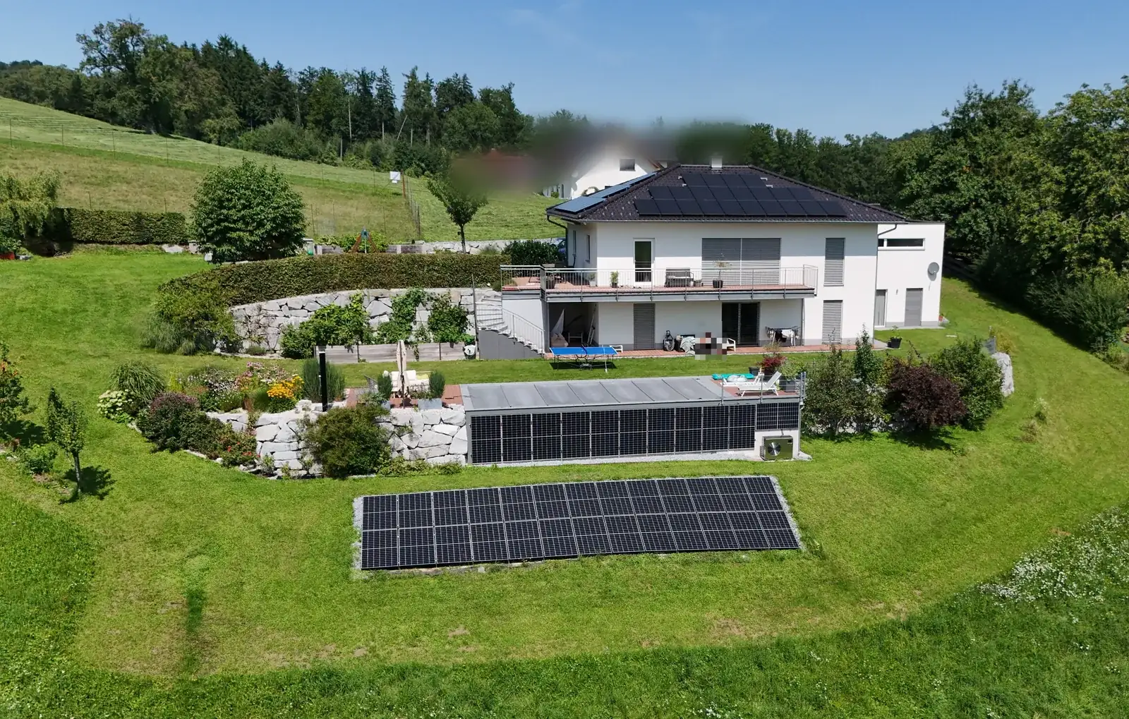 Einfamilienhaus mit Photovoltaik am Dach und Freiflächenanlage im Garten